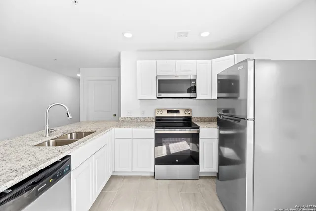 a kitchen with stainless steel appliances granite countertop a refrigerator sink and stove