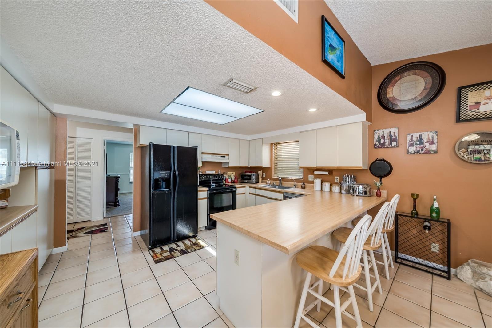 7921 Northwest 90th Avenue Tamarac, FL 33321 - Photo 16 of 69 a kitchen with stainless steel appliances kitchen island granite countertop a refrigerator a stove a microwave oven with a dining table and chairs