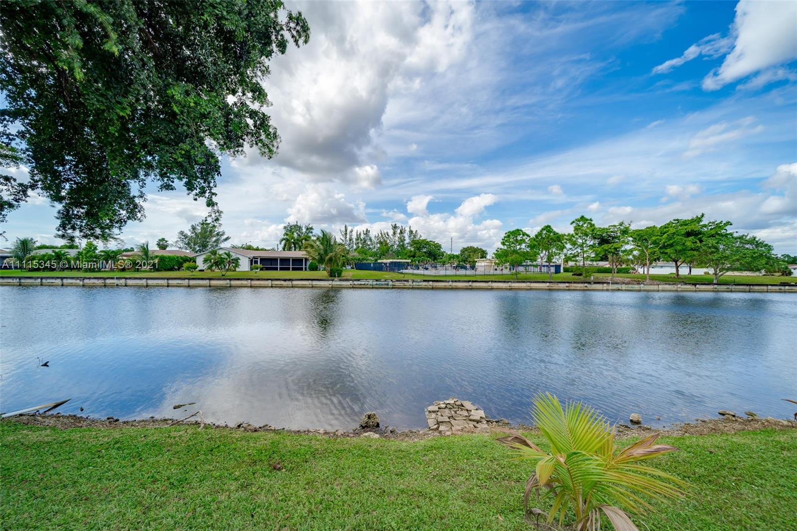 7921 Northwest 90th Avenue Tamarac, FL 33321 - Photo 55 of 69 a view of a lake with a big yard and large trees