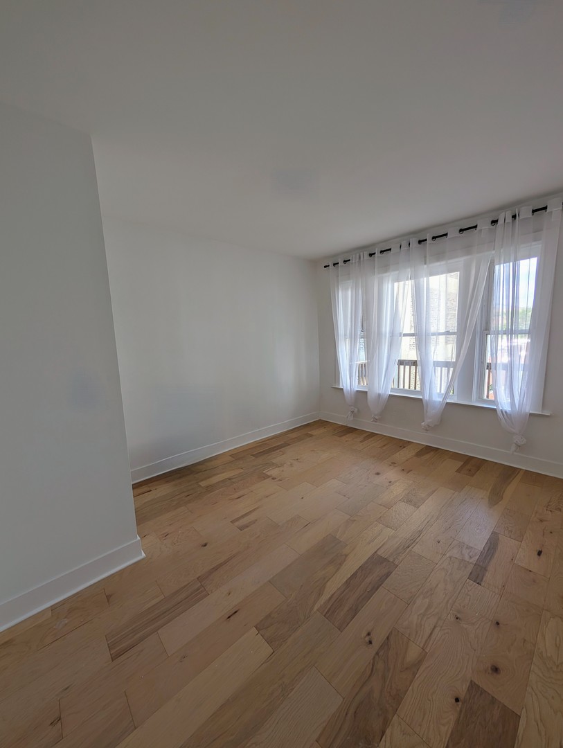 616 West Patterson Avenue, Unit 2W Chicago, IL 60613 - Photo 5 of 18 an empty room with wooden floor and windows