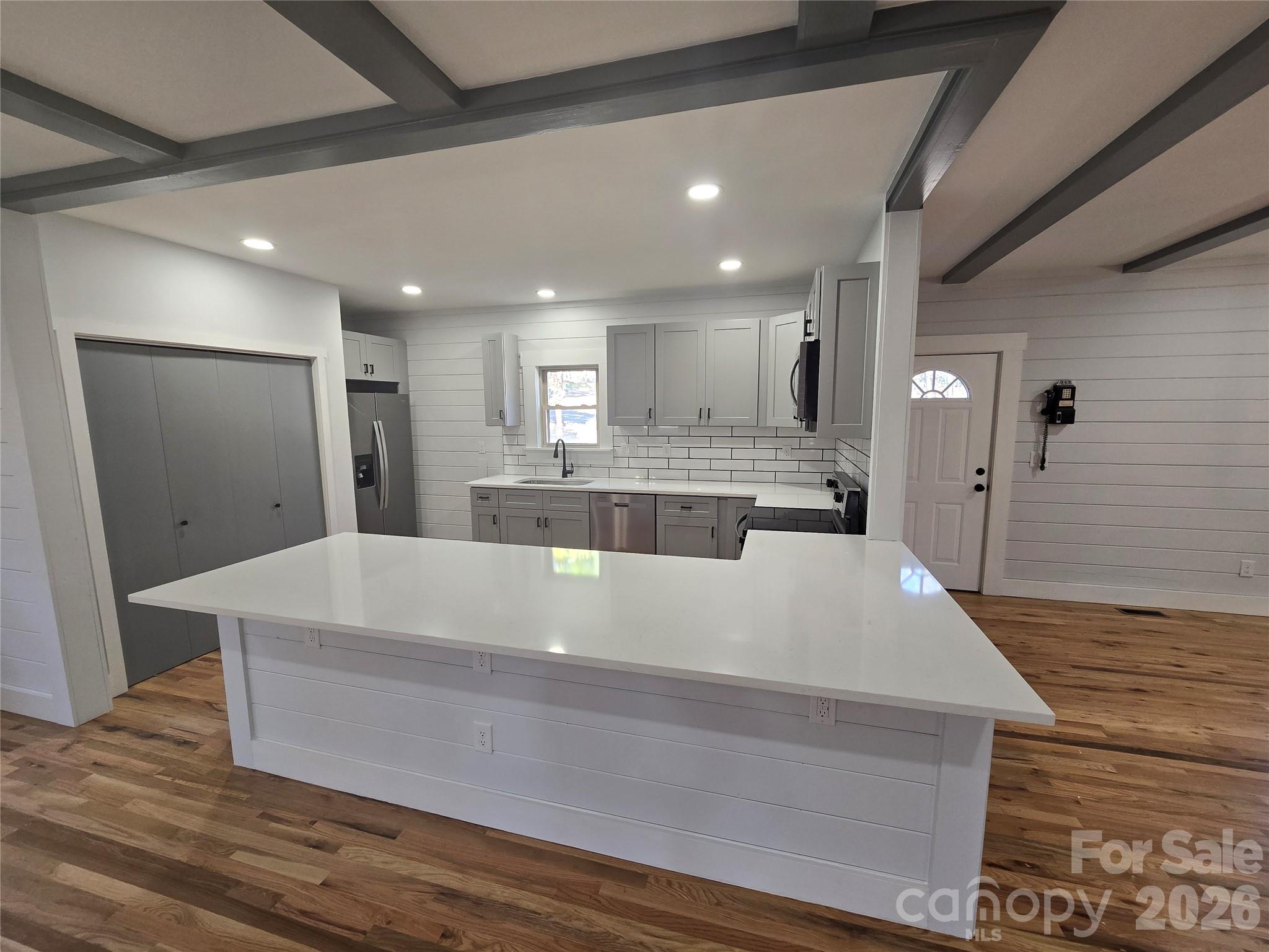 6802 Lowesville Lane Stanley, NC 28164 - Photo 12 of 25 a large white kitchen with wooden floors and stainless steel appliances