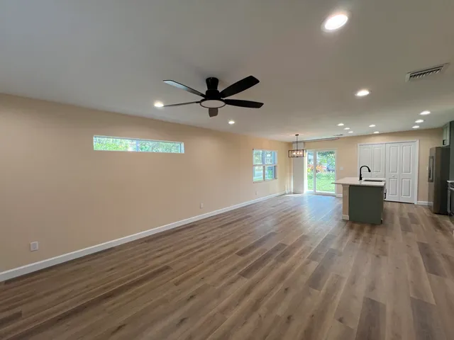 an empty room with wooden floor and a ceiling fan