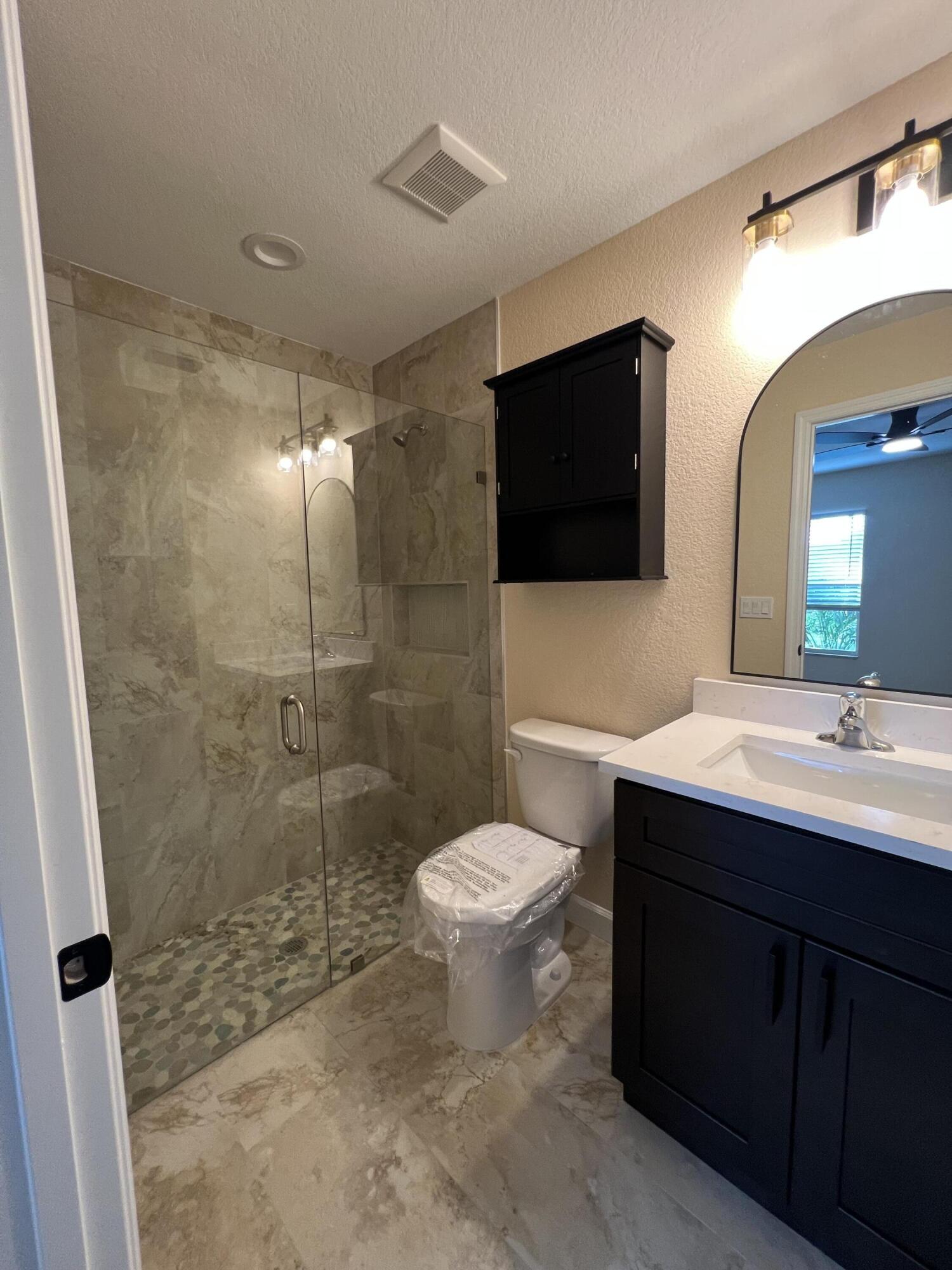 1001 Tennessee Avenue, Unit A Fort Pierce, FL 34950 - Photo 10 of 11 a bathroom with a sink toilet a mirror and shower