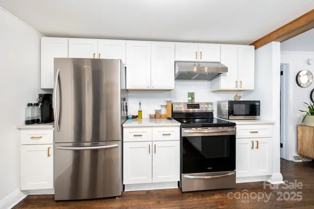 a kitchen with stainless steel appliances a refrigerator stove and white cabinets