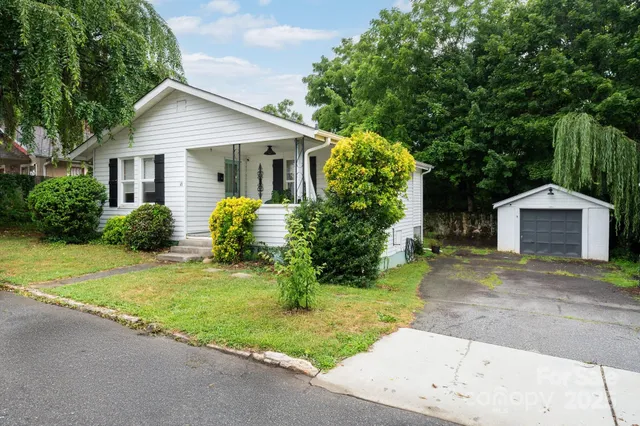 a view of a house with a yard and large trees