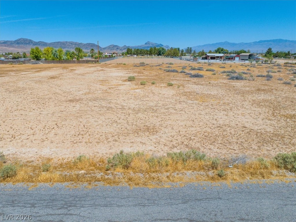 4610 Lawrence Road Pahrump, NV 89048 - Photo 5 of 42 A vast, level lot awaits, offering ample space for development amidst distant mountains.