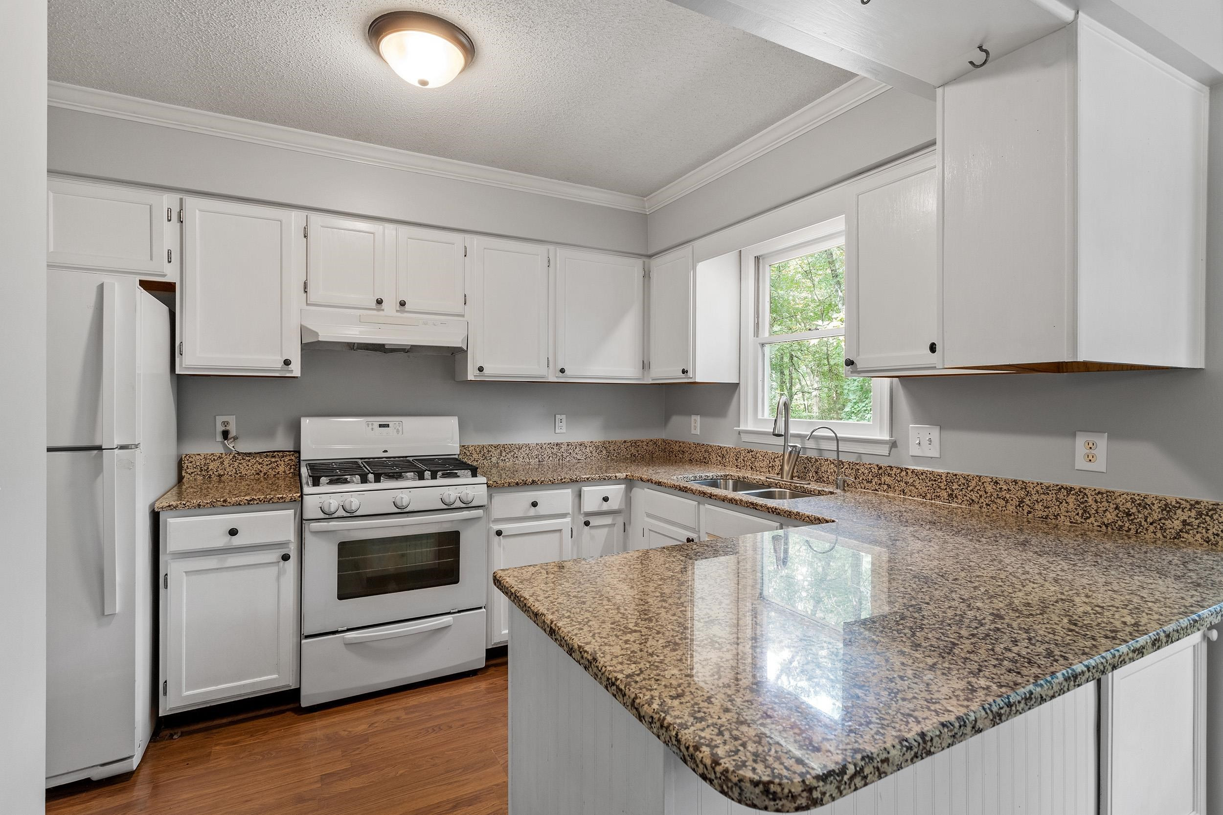 4 Hitching Rack Court Durham, NC 27713 - Photo 24 of 38 a kitchen with kitchen island granite countertop a sink stove and white cabinets