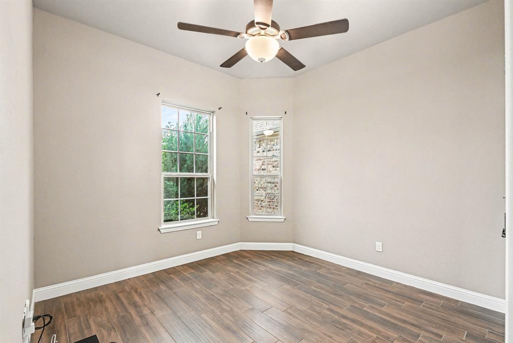 104 Stanford Lane Springtown, TX 76082 - Photo 23 of 28 an empty room with wooden floor chandelier fan and windows