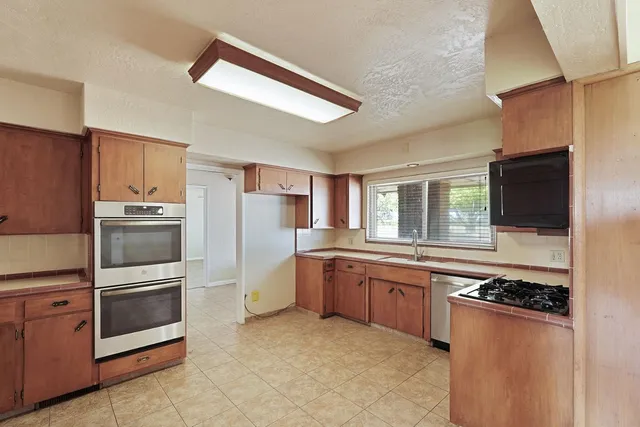 a kitchen with stainless steel appliances granite countertop a stove refrigerator sink and microwave