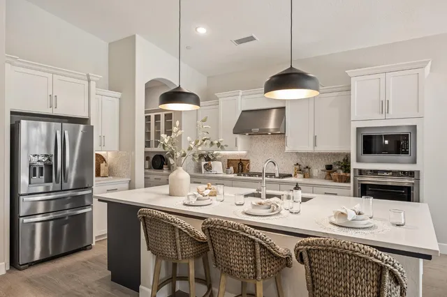 a kitchen with stainless steel appliances a stove a sink a refrigerator and a table