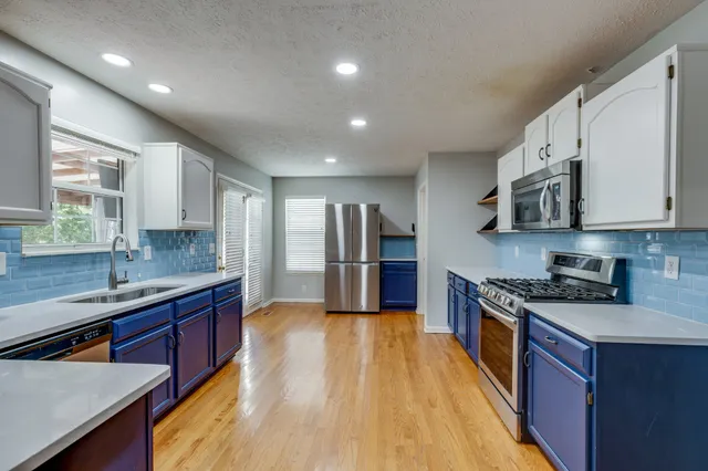 a kitchen with stainless steel appliances granite countertop wooden cabinets a sink dishwasher a stove and a refrigerator