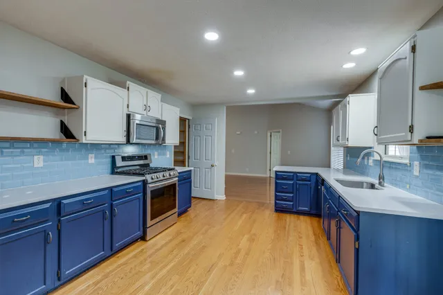 a large kitchen with stainless steel appliances granite countertop a stove a sink dishwasher and a refrigerator