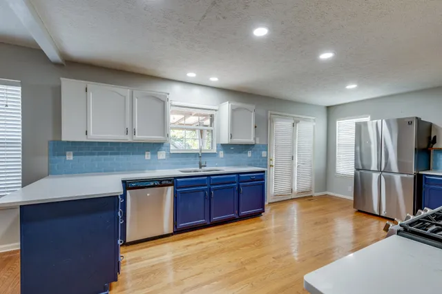 a kitchen with stainless steel appliances granite countertop a refrigerator a sink dishwasher a stove with wooden cabinets and floor