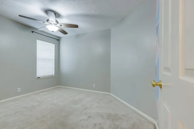 a view of an empty room with a chandelier fan