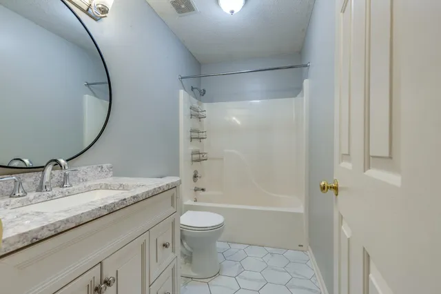 an empty room with chandelier fan and windows