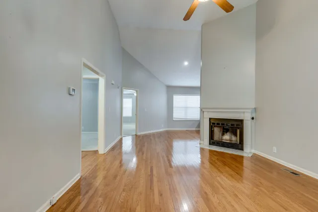 an empty room with wooden floor a fireplace and window