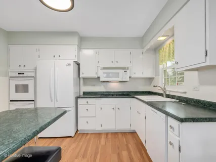 a kitchen with granite countertop white cabinets and white appliances