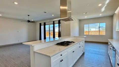 a kitchen with granite countertop stainless steel appliances sink stove refrigerator and cabinets