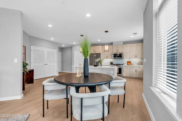 a kitchen with stainless steel appliances kitchen island granite countertop a dining table chairs and a refrigerator