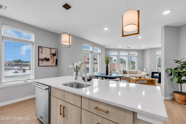 a view of living room with stainless steel appliances granite countertop a sink and a large window