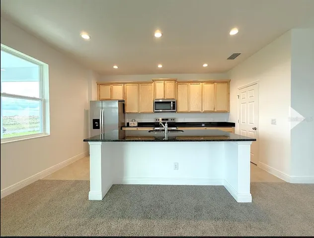 a kitchen with stainless steel appliances granite countertop a sink a stove a refrigerator a microwave and island