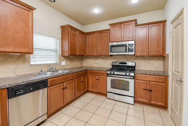 a kitchen with granite countertop cabinets stainless steel appliances and a sink
