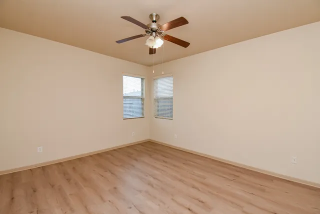 an empty room with wooden floor and ceiling fan