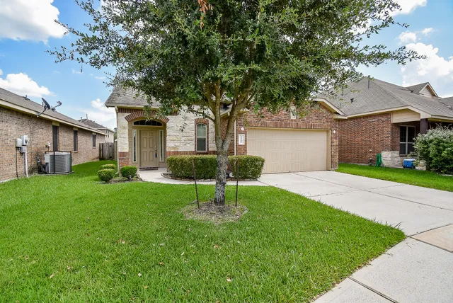 a front view of a house with a yard and tree