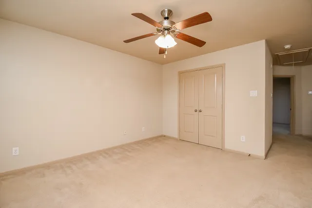 an empty room with closet and a ceiling fan