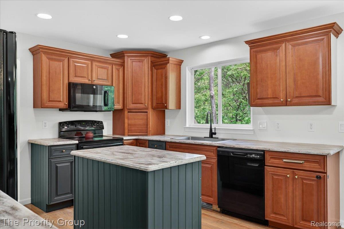 517 Deer Valley Road Holly, MI 48442 - Photo 10 of 61 Kitchen with black appliances, neutral wood flooring, light colored corian countertops