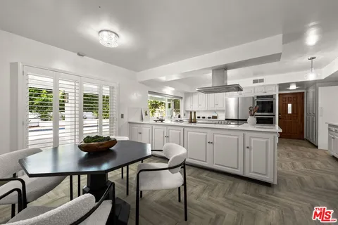 a kitchen with stainless steel appliances kitchen island granite countertop a dining table chairs and window