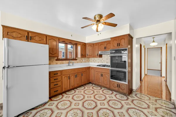 a kitchen with stainless steel appliances granite countertop a refrigerator a sink and white cabinets