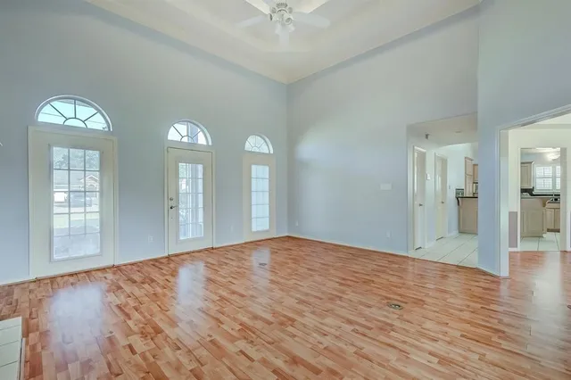 a view of an empty room with wooden floor and a window
