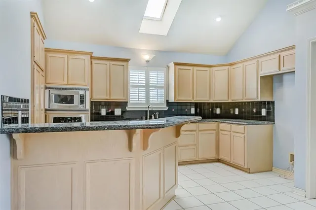 a kitchen with stainless steel appliances granite countertop white cabinets granite counter tops and a window