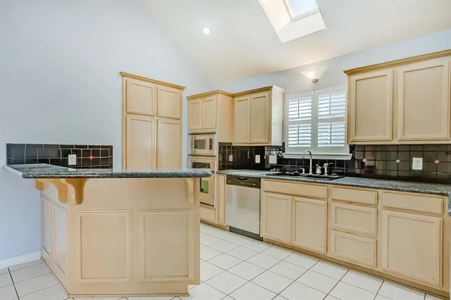 a kitchen with stainless steel appliances granite countertop a sink and a refrigerator