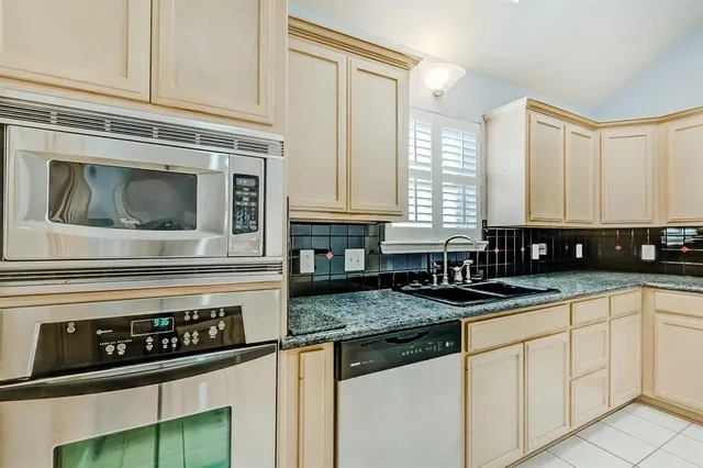 a kitchen with granite countertop a stove a sink and cabinets