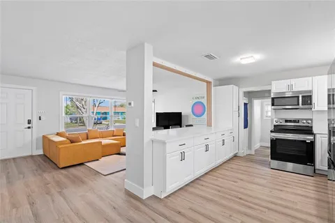 a large living room with stainless steel appliances kitchen island hard wood floors and furniture