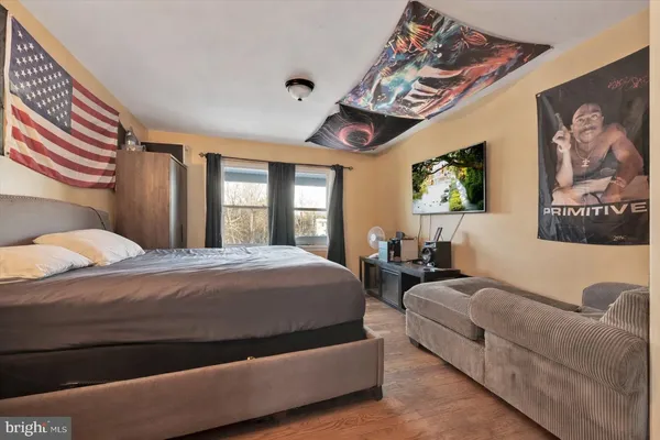a spacious bedroom with a bed a painting on the wall and a large window
