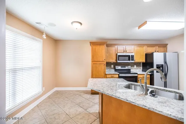 a kitchen with stainless steel appliances granite countertop a sink a stove a refrigerator a window with wooden floor and cabinets