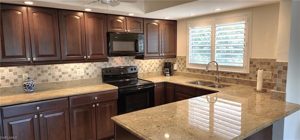 102 Georgetown Boulevard, Unit 102 Naples, FL 34112 - Photo 9 of 29 a kitchen with granite countertop a sink stainless steel appliances and cabinets