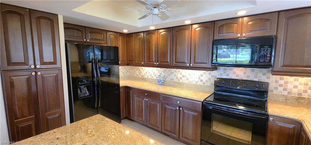 102 Georgetown Boulevard, Unit 102 Naples, FL 34112 - Photo 10 of 29 a kitchen with stainless steel appliances granite countertop a refrigerator and a stove top oven