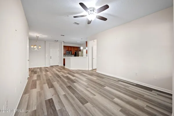 a view of empty room with wooden floor and fan