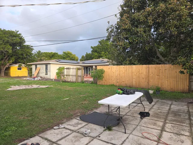 a view of a backyard with table and chairs potted plants and large tree