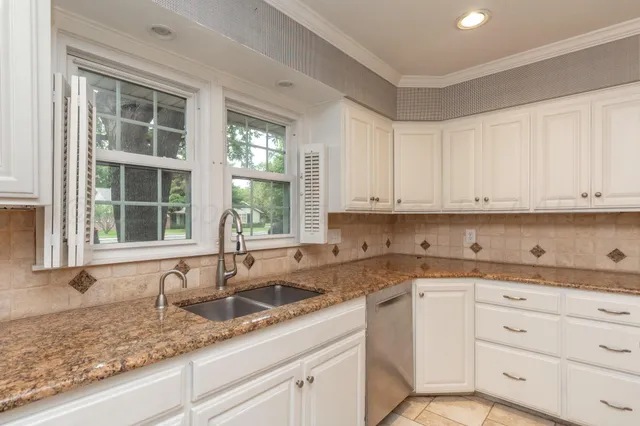 a kitchen with granite countertop white cabinets and window