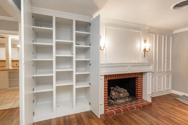 a living room with a fireplace and a walk in closet with wooden floor