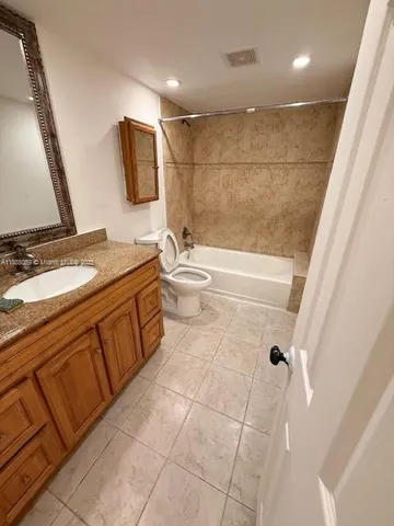 a bathroom with a granite countertop sink a toilet and mirror
