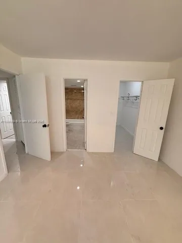 an empty room with white wall and wooden door