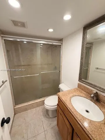 a bathroom with a granite countertop sink a toilet a mirror and shower