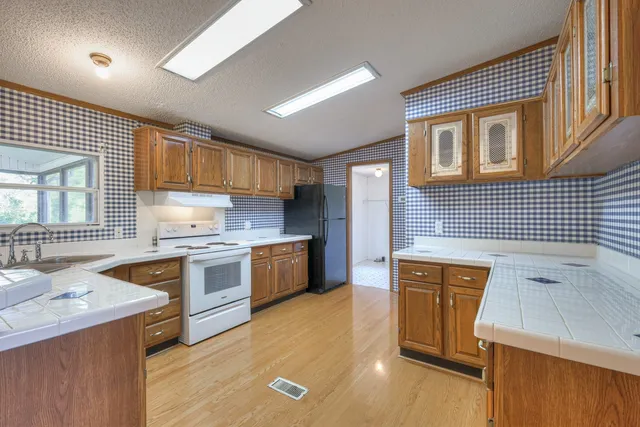 a kitchen with stainless steel appliances granite countertop sink stove top oven and cabinets