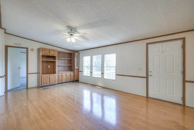 a view of an empty room with window and wooden floor